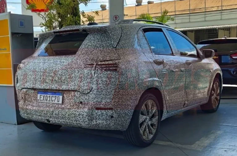 La parte trasera de un auto cubierto con vinilo de camuflaje en una estación de servicio.