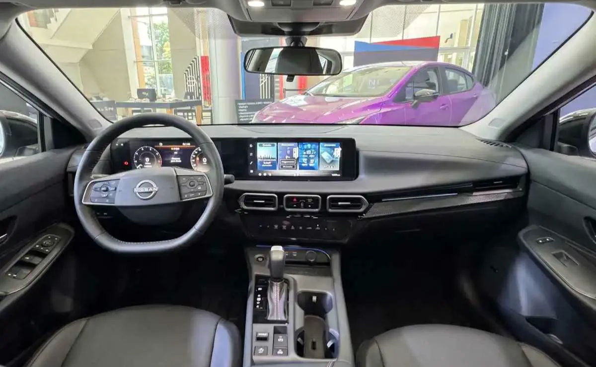 Tablero, volante y pantalla digital del interior de un auto con tapizado negro.