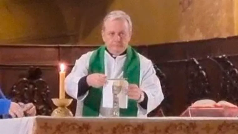 Un sacerdote con vestidura blanca y estola verde sostiene un paño frente al altar durante una misa.