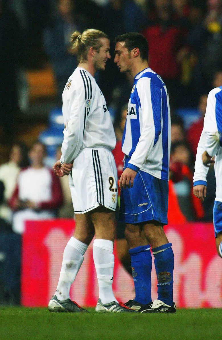 David Beckham y Lionel Scaloni mirándose de frente muy cerca durante un partido de fútbol.