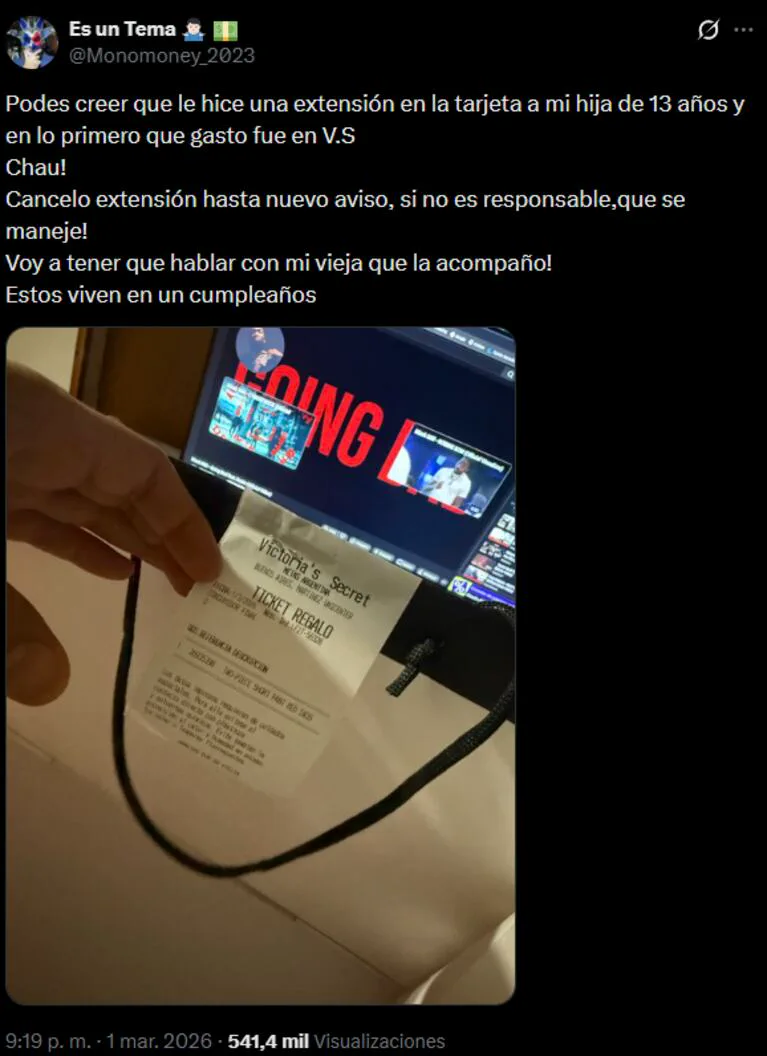 Una mano sostiene un ticket de compra frente a la pantalla de una computadora portátil con un video abierto.