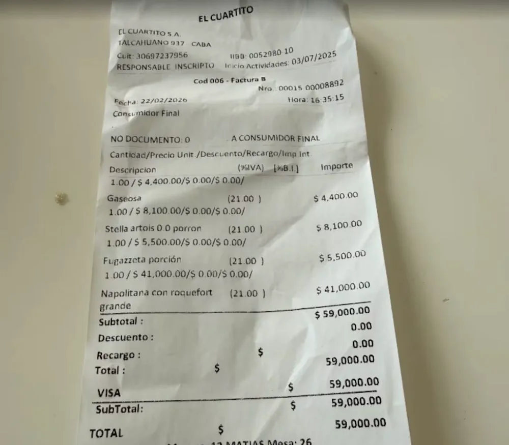 Ticket de factura fiscal emitido por la pizzería El Cuartito sobre una mesa blanca con consumos detallados.
