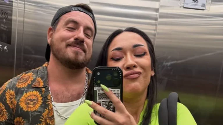 Federico Bal y una mujer sonriendo frente al espejo dentro de un ascensor mientras ella se saca una selfie con el celular.