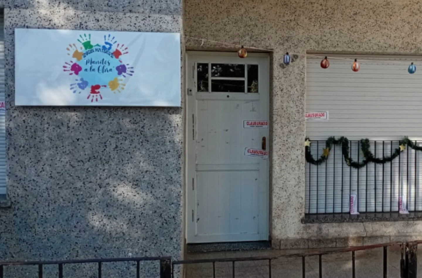 Frente del jardin maternal Manitos a la Obra con fajas de clausura en la puerta y rejas.