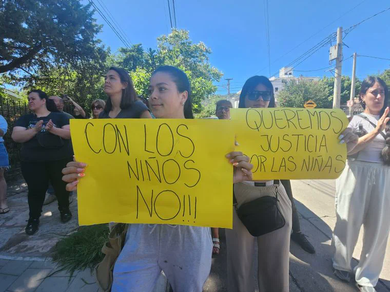 Personas sostienen cartulinas amarillas con reclamos manuscritos durante una manifestación en la calle.