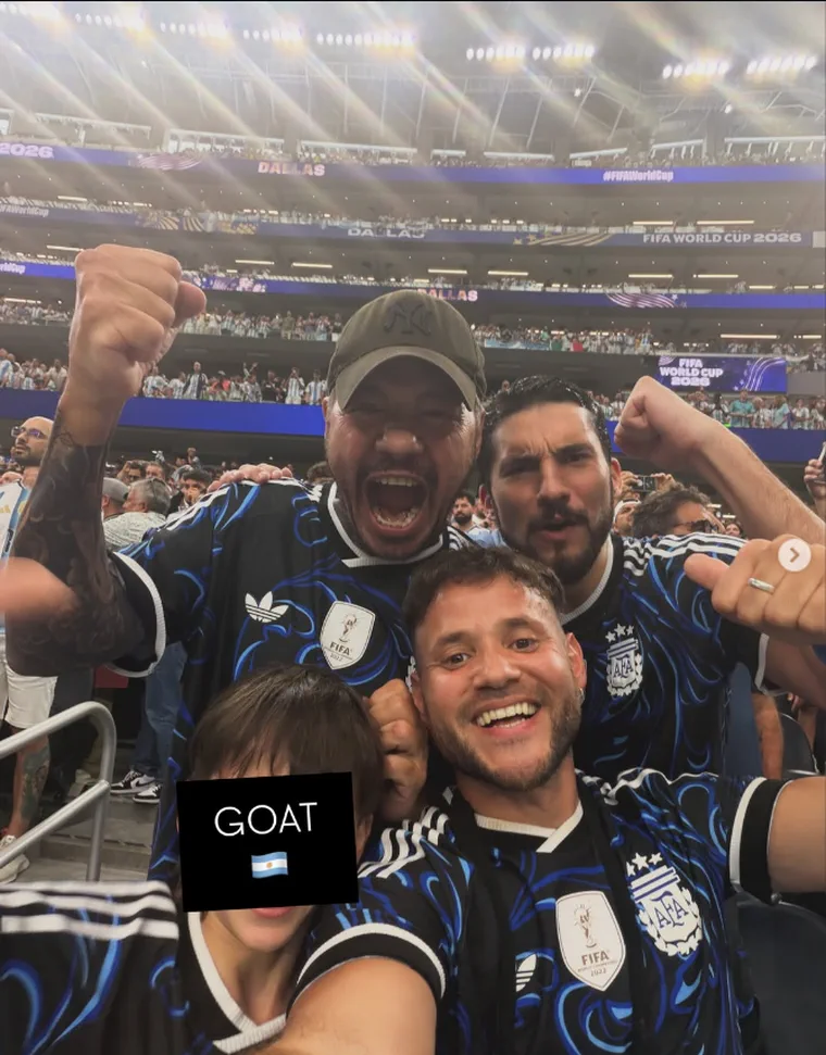 Tres hombres y un nene con la camiseta de la seleccion argentina festejan en una tribuna de estadio.