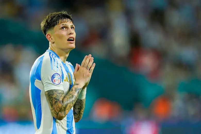 El futbolista Alejandro Garnacho mira hacia arriba con las manos juntas vistiendo la camiseta argentina.