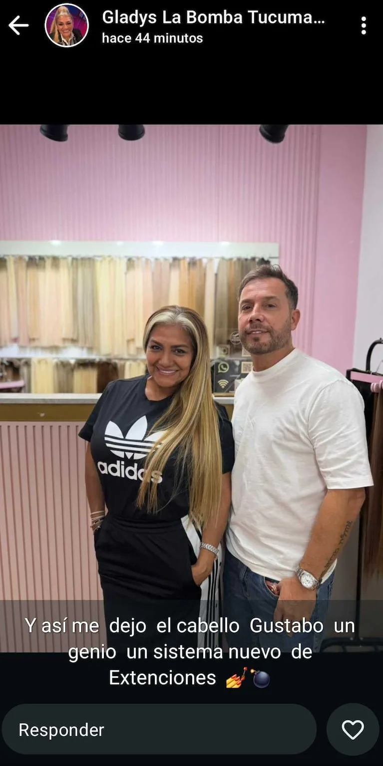 Gladys la Bomba Tucumana posa sonriendo junto a un peluquero en un local con muestras de extensiones de pelo.