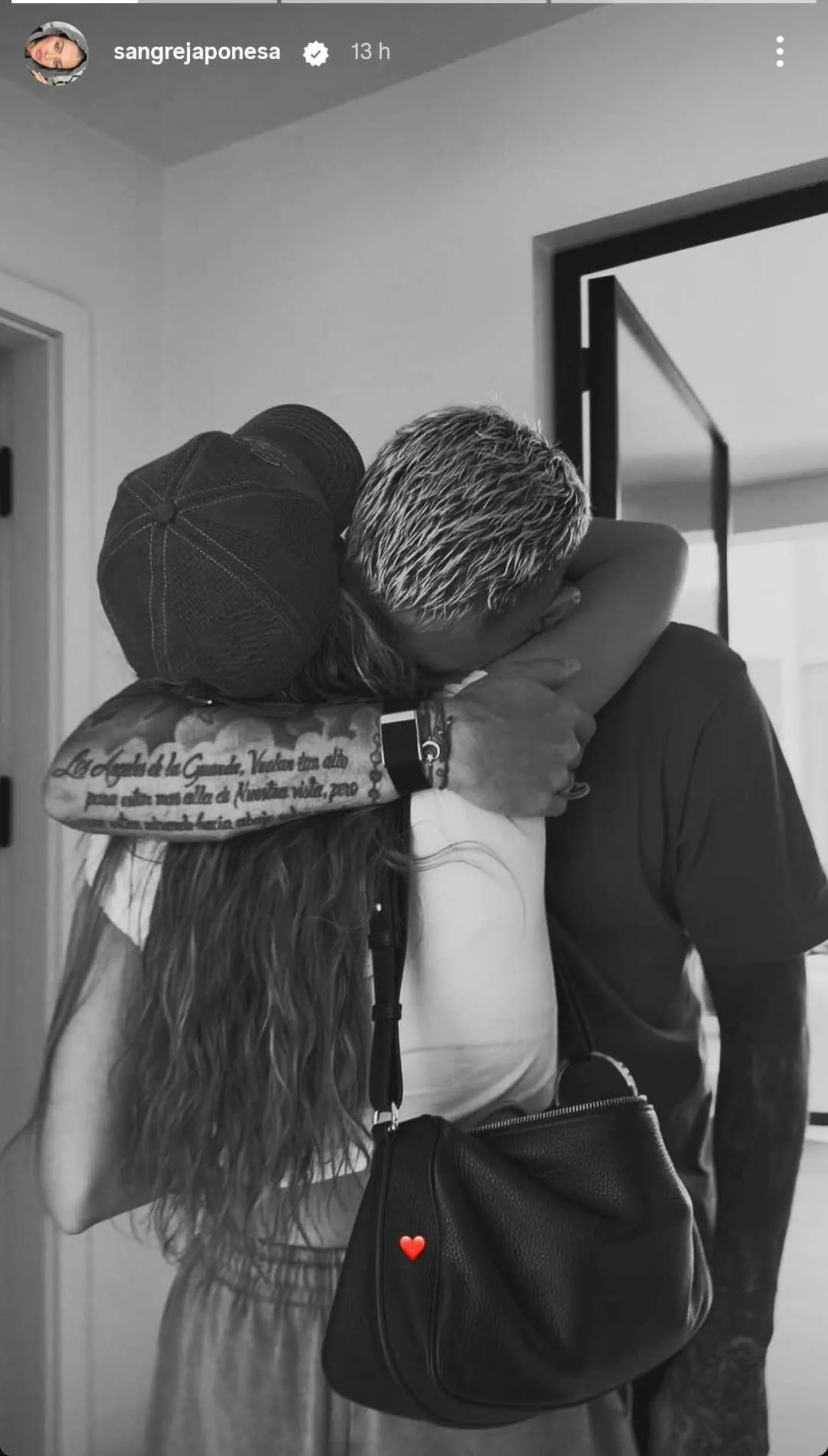 Una mujer con gorra y un hombre con el pelo teñido se abrazan de espaldas en una historia en blanco y negro.