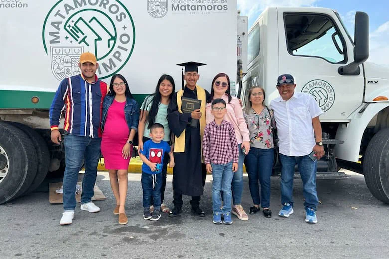 Un grupo de personas posa al aire libre frente a un camión blanco de recolección de residuos de Matamoros.