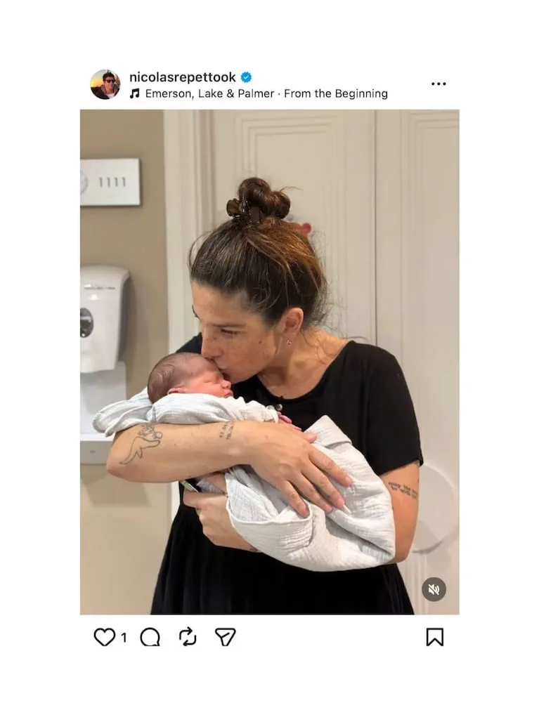 Juana Repetto sostiene en brazos y besa la frente de un bebé recién nacido envuelto en una manta blanca.