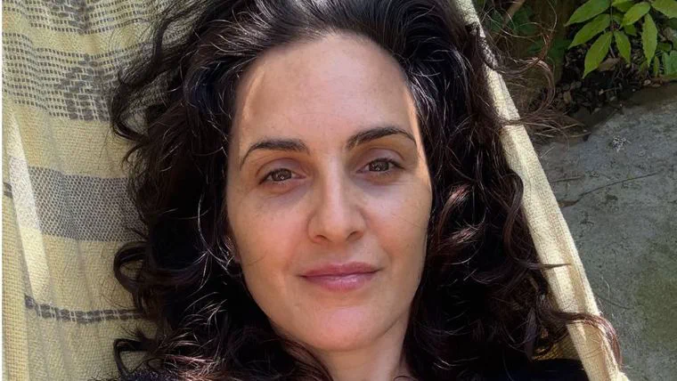 La actriz Julieta Díaz recostada sobre una hamaca paraguaya al aire libre mirando a la cámara.