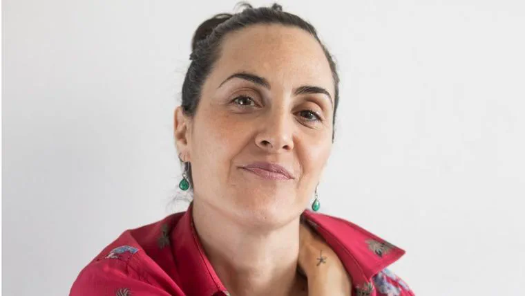 La actriz Julieta Díaz con camisa fucsia estampada y aros colgantes mirando al frente contra un fondo blanco.