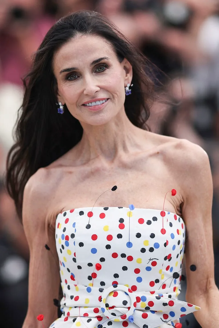 Demi Moore sonríe en primer plano luciendo un vestido blanco strapless a lunares de colores.