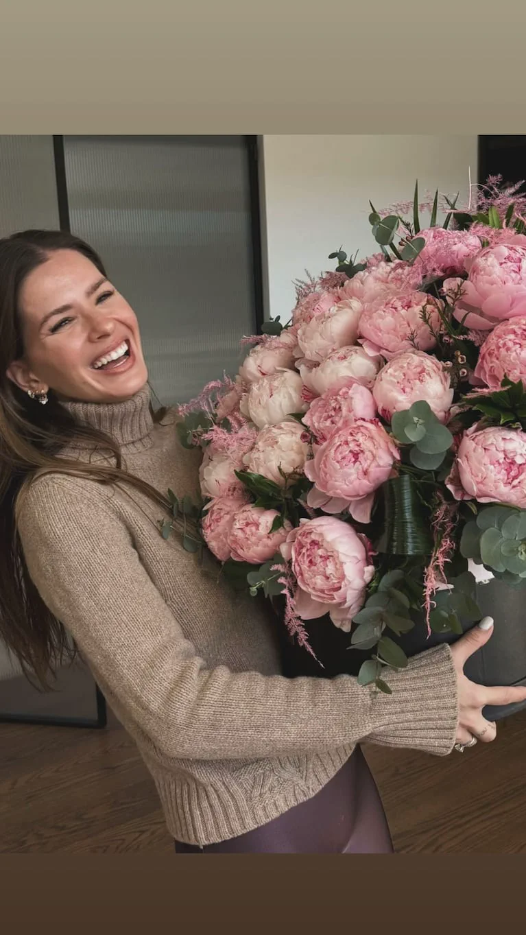 La China Suárez sostiene un ramo enorme de peonías rosas mientras se ríe.