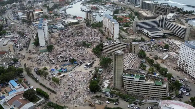 Vista aérea de una ciudad costera con múltiples edificios y manzanas completamente derrumbados y reducidos a escombros.