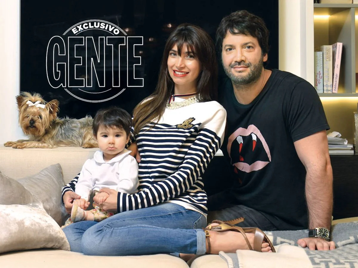 Un hombre, una mujer y una beba estan sentados en un sillon junto a un perro pequeno, bajo un logo que dice GENTE.