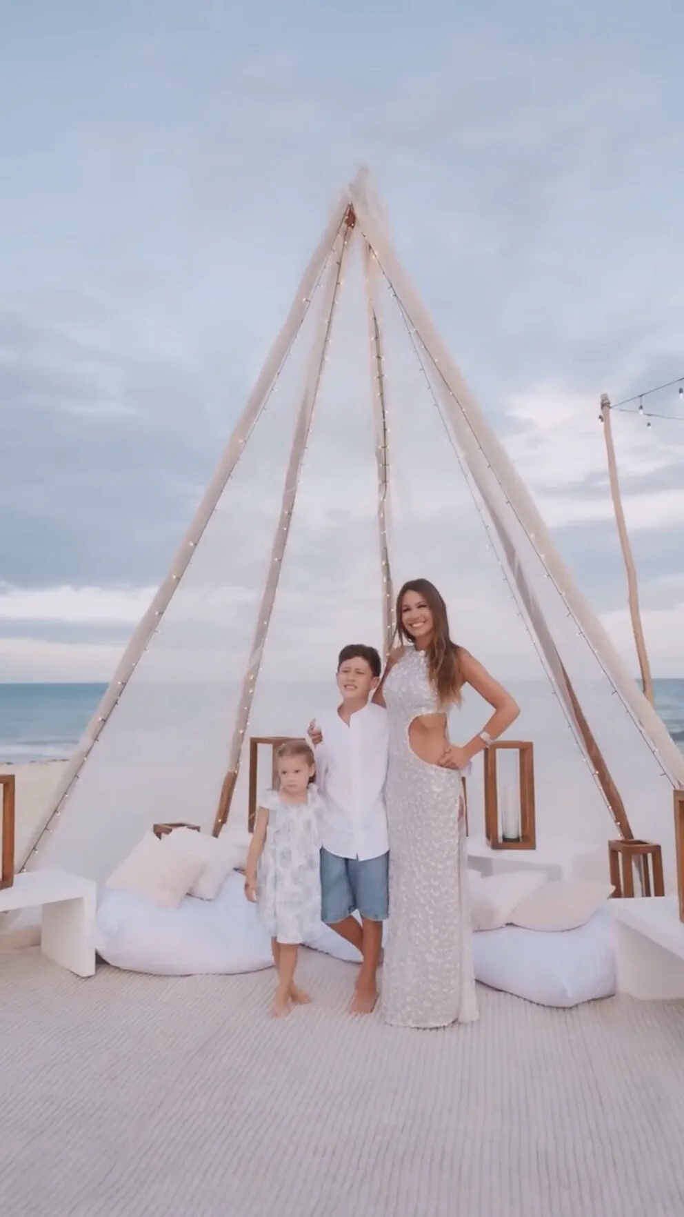 Pampita posa en la playa junto a dos nenes bajo una estructura con forma de carpa india.