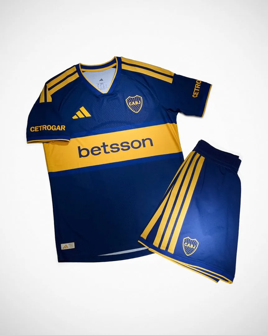 Camiseta y pantalón corto azules con detalles amarillos y escudo de Boca Juniors sobre fondo claro.