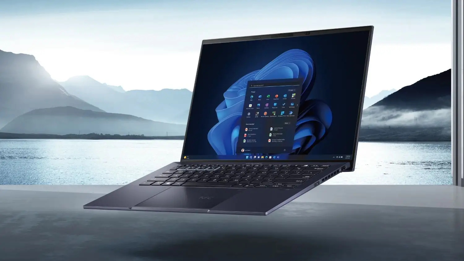 Una notebook abierta flota en el aire mostrando la pantalla de inicio del sistema operativo con un lago de fondo.