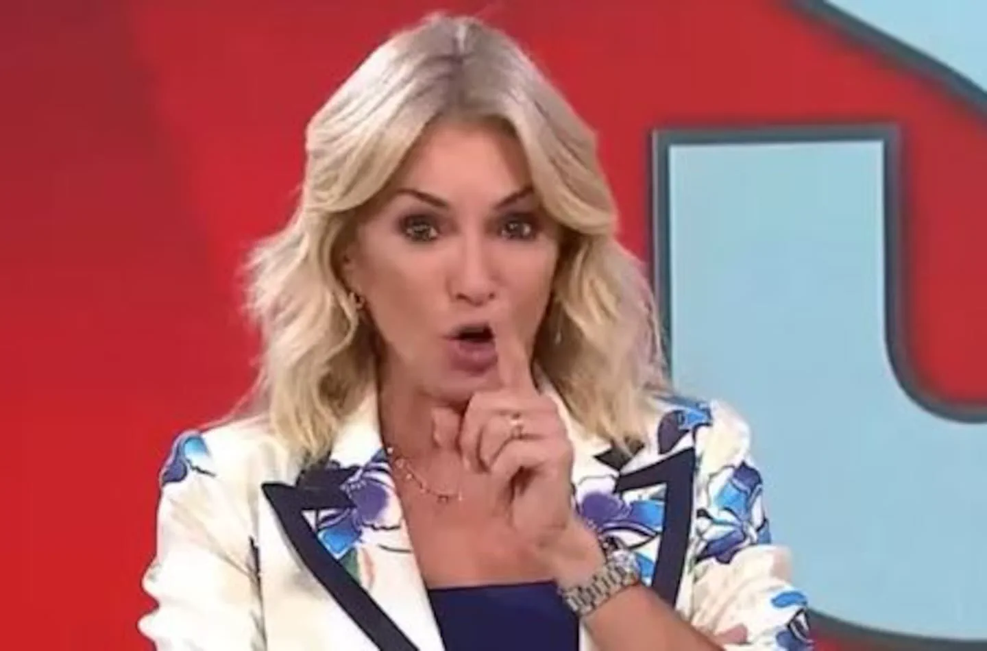 Yanina Latorre gesticula pidiendo silencio frente a una cámara de televisión.