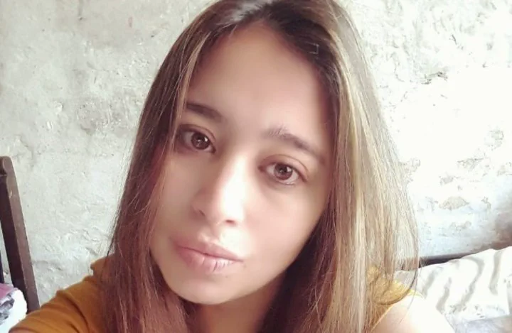 Una chica de pelo castaño claro se saca una selfie en un ambiente de pared rústica.