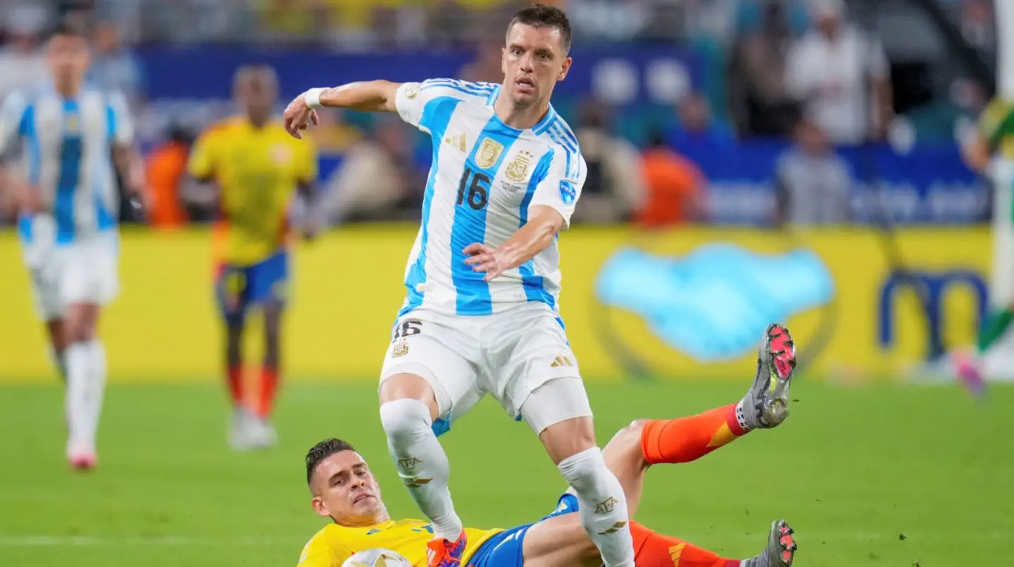 Giovani Lo Celso elude a un rival que barre sobre el césped durante un partido de fútbol.