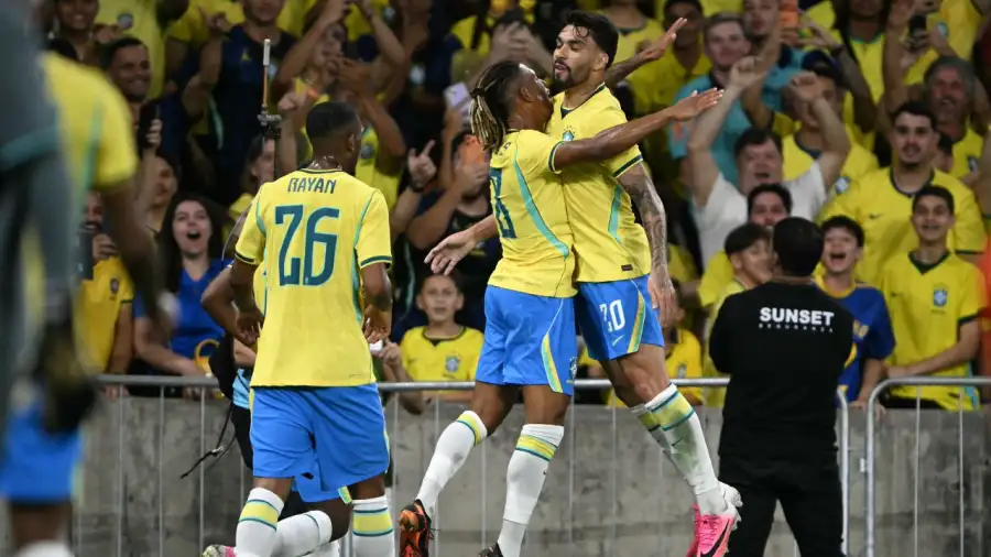 Jugadores de la selección de fútbol de Brasil festejan un gol abrazándose frente a la tribuna con hinchas.