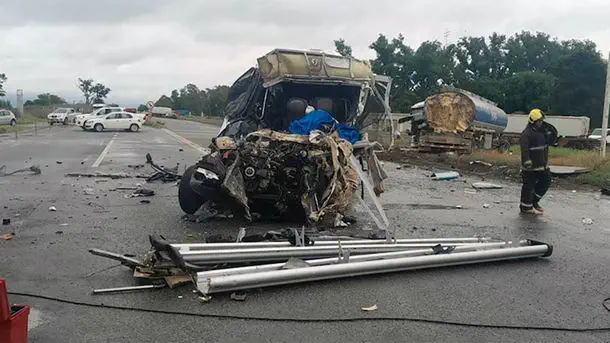 Un vehículo destrozado por un choque y restos metálicos esparcidos sobre el asfalto.