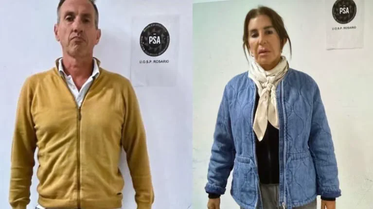 Un hombre con campera amarilla y una mujer con campera azul posan frente a carteles de la PSA Rosario.