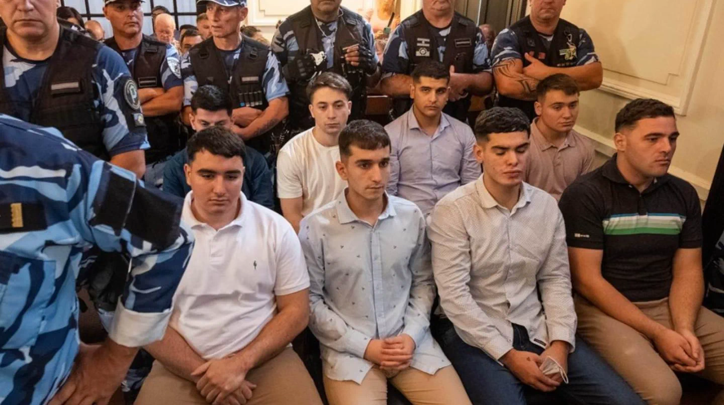 Los rugbiers condenados por el crimen de Fernando Báez Sosa sentados durante el juicio custodiados por policías.