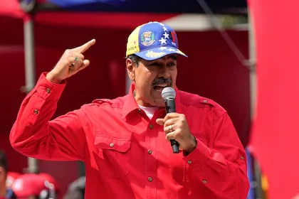 Nicolás Maduro hablando por micrófono con camisa roja y gorra con los colores de la bandera venezolana.