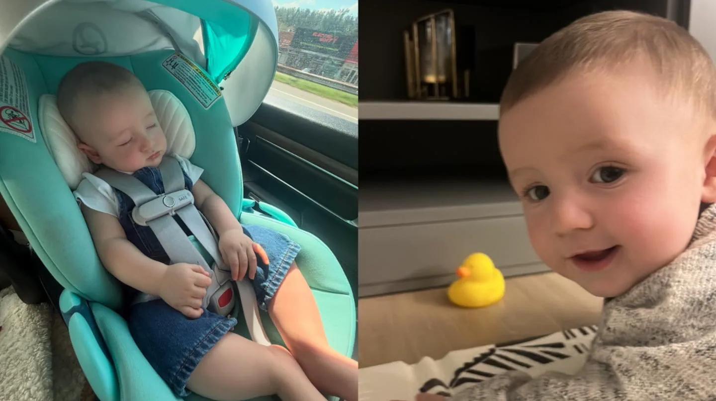 Un bebe durmiendo en una sillita de auto al lado de un nene sonriendo en el piso con un patito de goma.