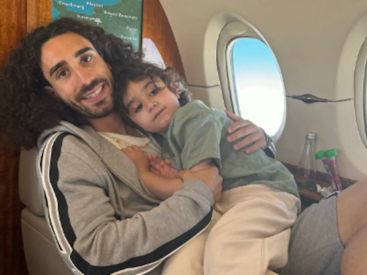 Marc Cucurella sostiene a un niño a upa mientras viajan sentados dentro de un avión privado.