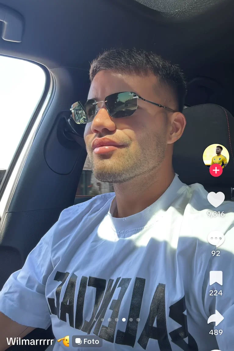 Un joven con anteojos de sol y remera blanca va sentado adentro de un auto mientras mira hacia el costado.