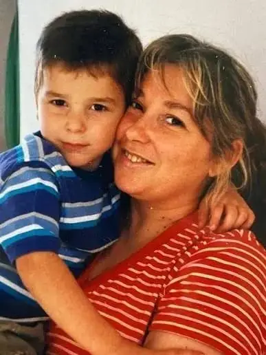Una mujer sonriente abraza a un nene a upa con remera a rayas.
