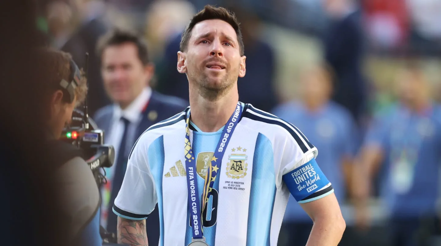 Lionel Messi lleva puesta la camiseta argentina y una medalla al cuello mientras mira hacia arriba.