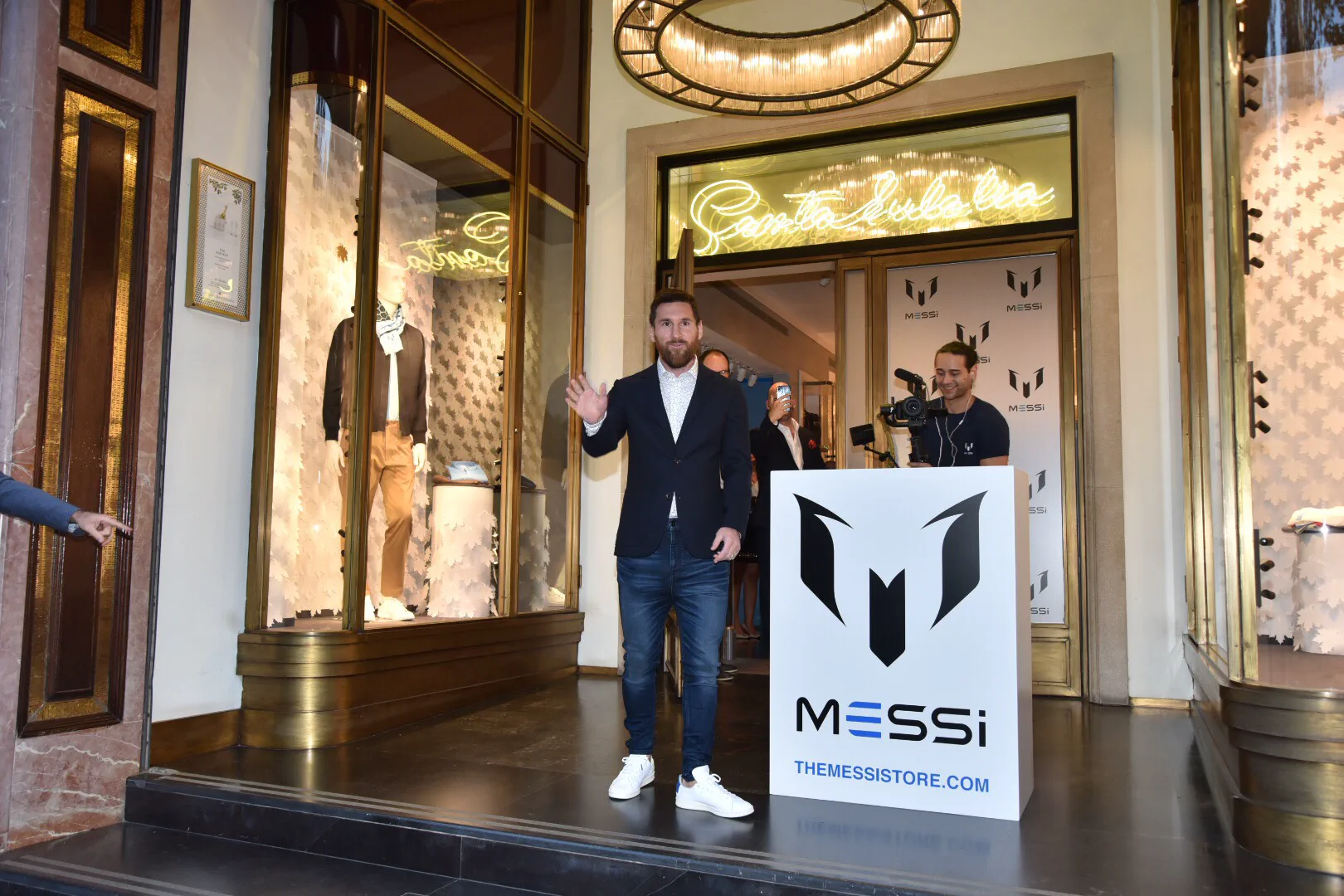 Lionel Messi sonriendo y saludando con la mano en la inauguracion de un local de ropa de su marca.