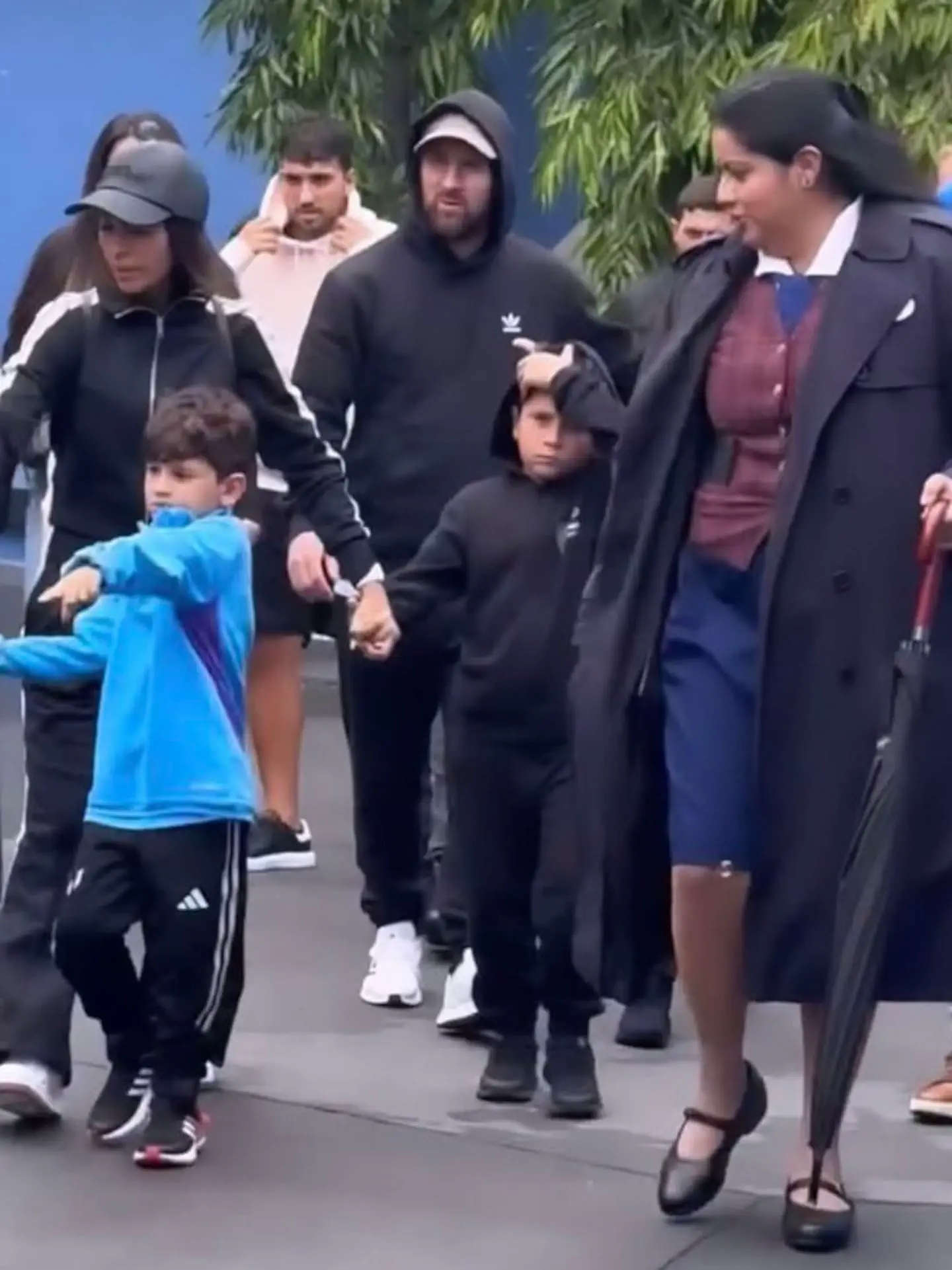 Lionel Messi y Antonela Roccuzzo caminan junto a sus hijos y una mujer vestida con sobretodo negro.