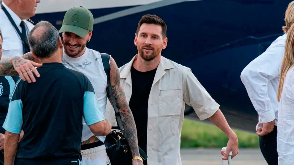 Lionel Messi camina sonriendo junto a Rodrigo De Paul al aire libre.