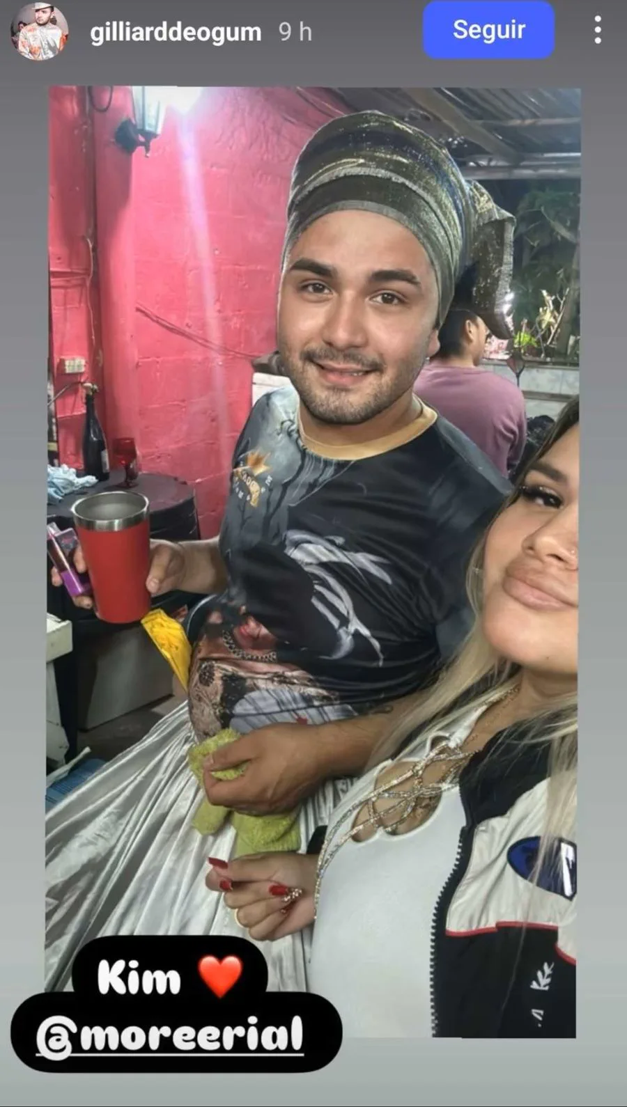 Morena Rial se saca una selfie junto a un hombre con turbante y una copa roja en una habitacion.