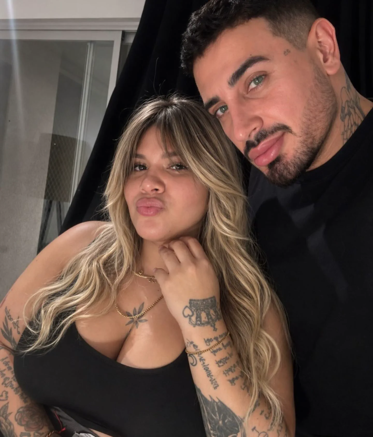 Morena Rial posa haciendo trompita junto a un hombre con tatuajes en el cuello y los brazos.