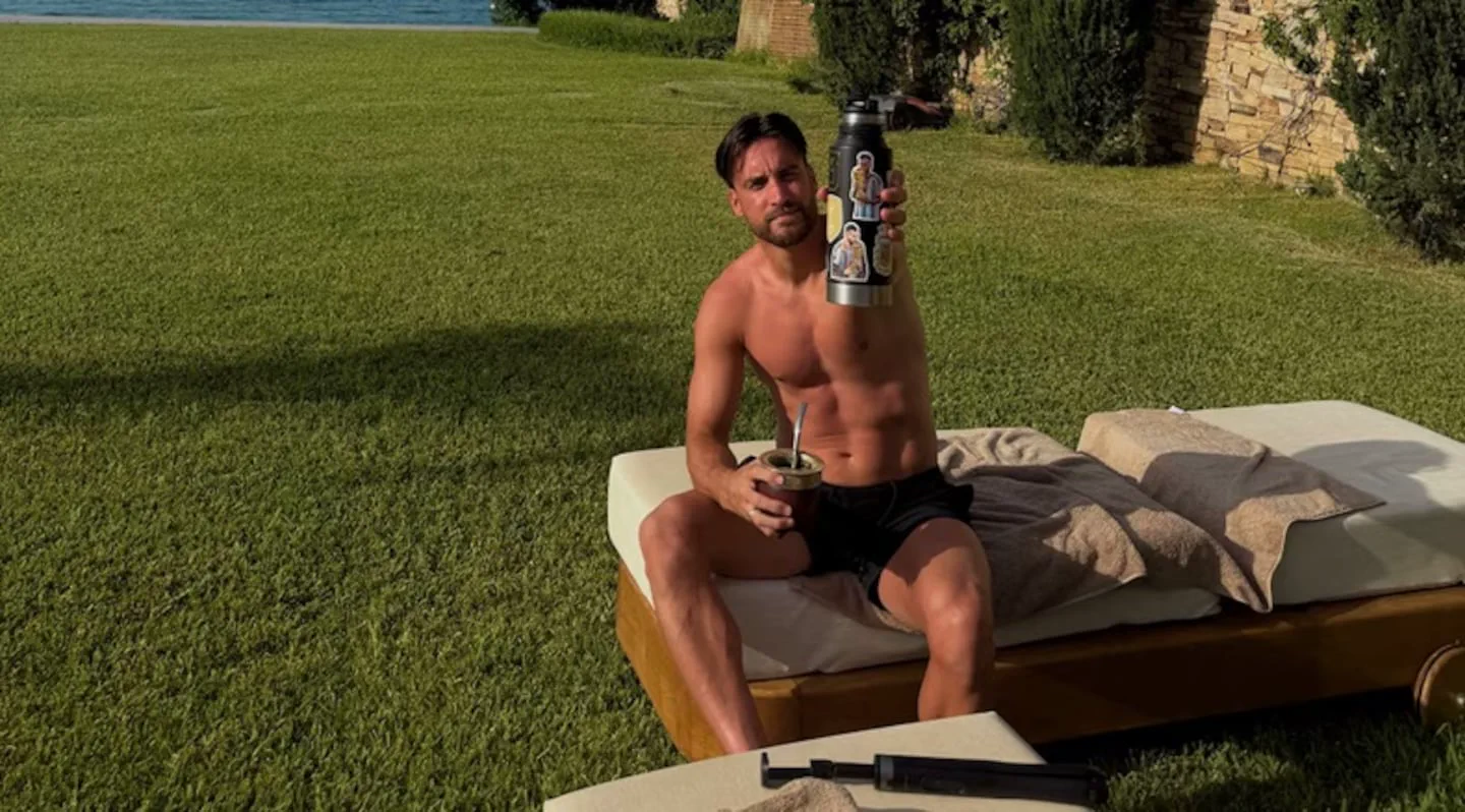 El futbolista Nicolás Tagliafico toma mate y sostiene un termo en una reposera al aire libre.