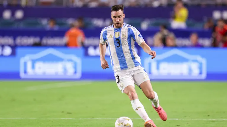 Nicolás Tagliafico corre con la pelota vistiendo la camiseta de la selección argentina en una cancha de fútbol.