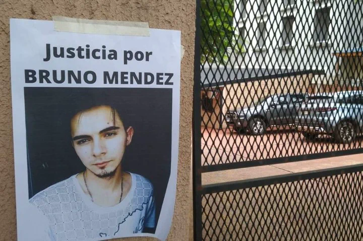 Un cartel con la foto de un joven y la frase Justicia por Bruno Mendez pegado junto a una reja negra.