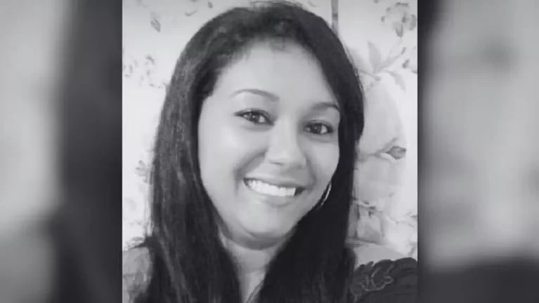 Retrato en blanco y negro en primer plano de una mujer sonriendo frente a un fondo con flores.
