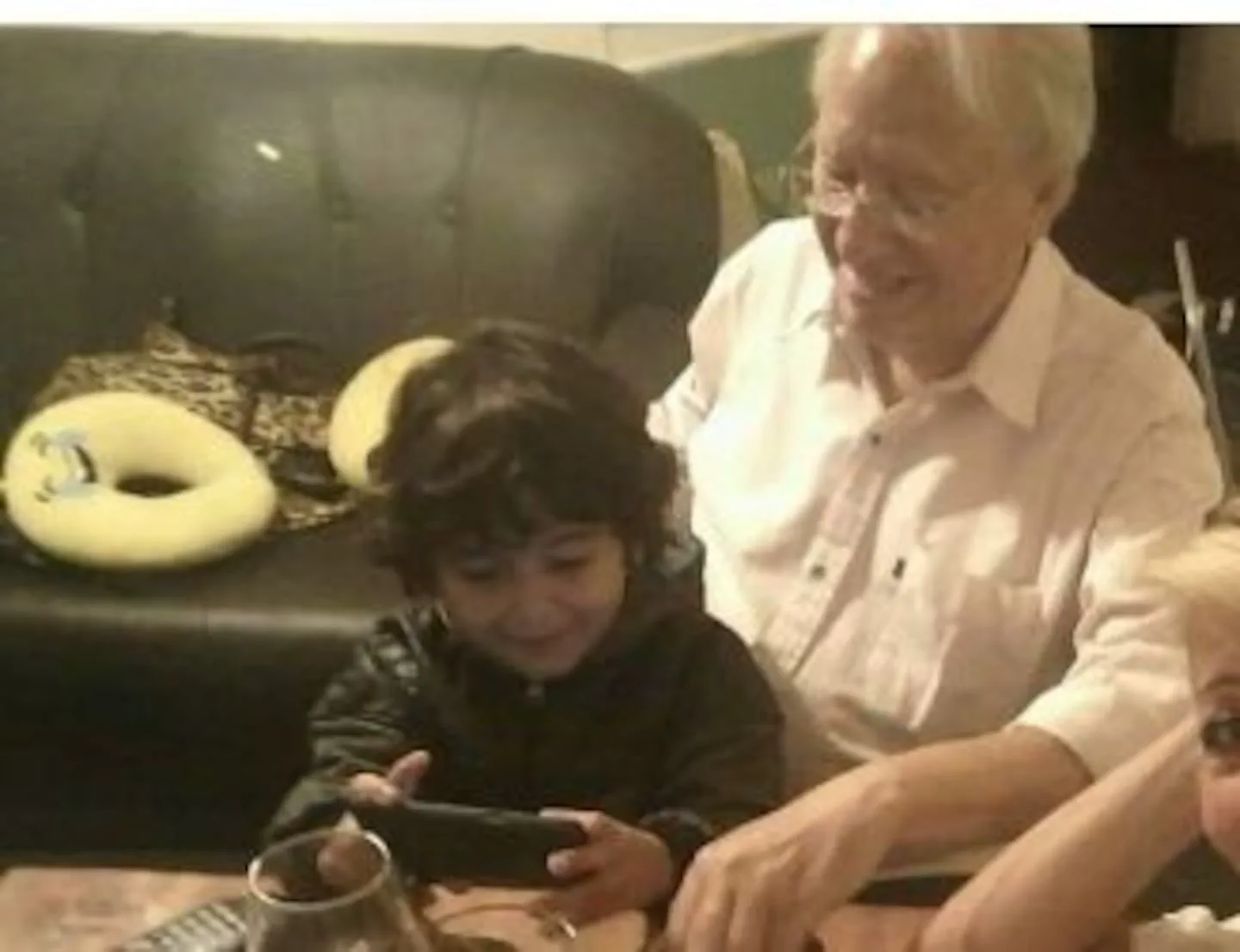 Un nene y un hombre mayor sentados juntos mirando la pantalla de un celular.