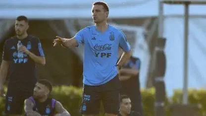 Lionel Scaloni da indicaciones de pie con remera celeste de entrenamiento de la selección argentina.