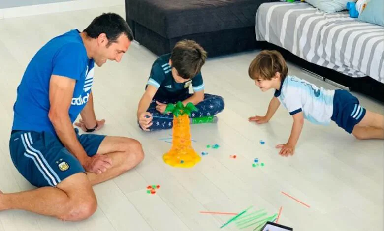 Lionel Scaloni juega en el piso con sus dos hijos alrededor de una palmera de juguete.
