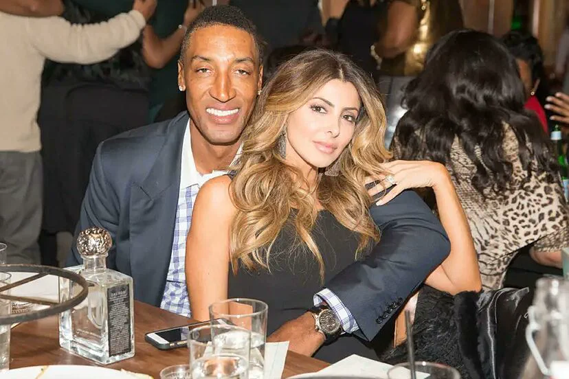 Scottie Pippen y Larsa Pippen abrazados sonrien sentados a una mesa durante un evento nocturno.